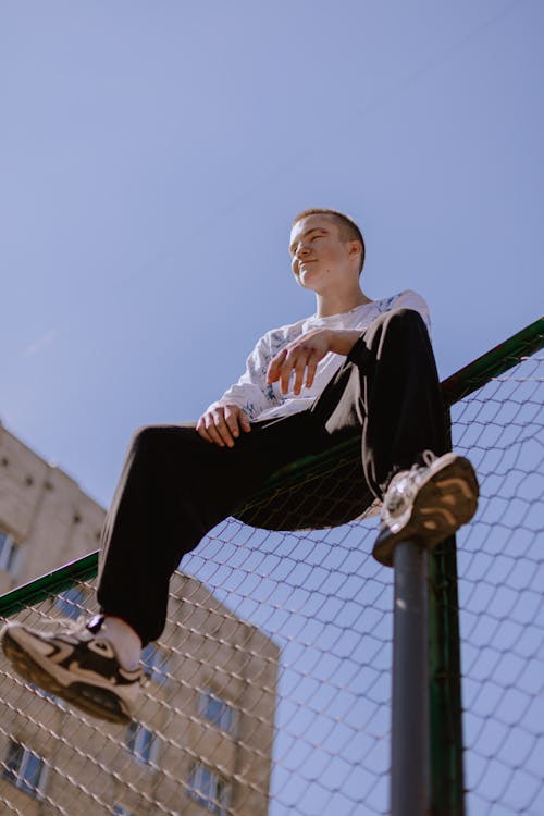 Boy Sitting on Top of a Fence