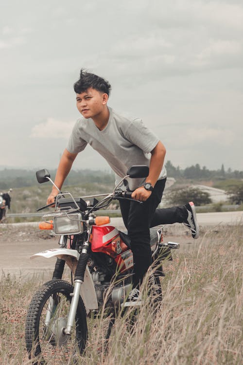 Man in Gray Shirt Riding a Motor Bike on Brown Grass