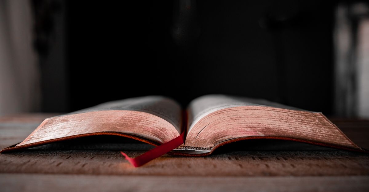ancient leather-bound prayer book open on a wooden desk with morning light streaming in