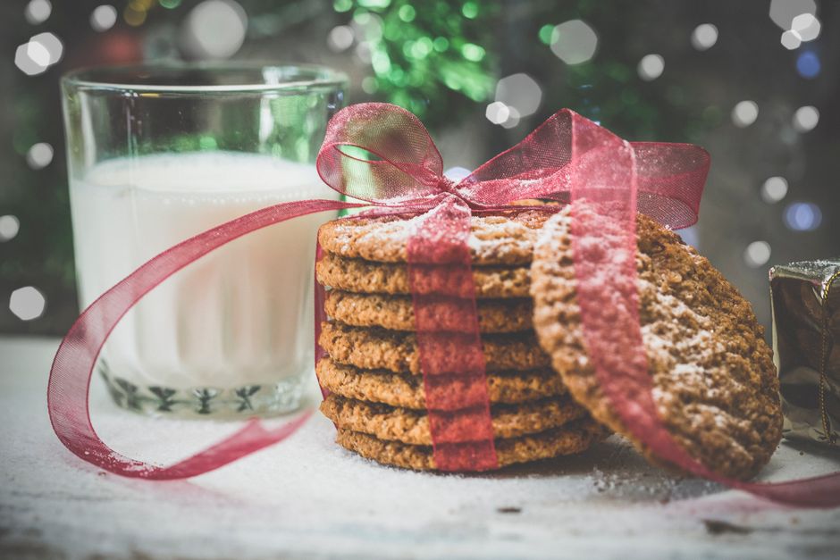 Christmas oatmeal cookies tied with red ribbon next to a glass of milk. Perfect for festive occasions.