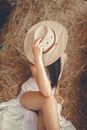 Woman in White Shirt and White Shorts Wearing Brown Hat Sitting on Brown Dried Grass