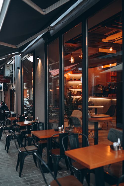 Free Charming outdoor café setting with modern glass facade and inviting atmosphere. Stock Photo