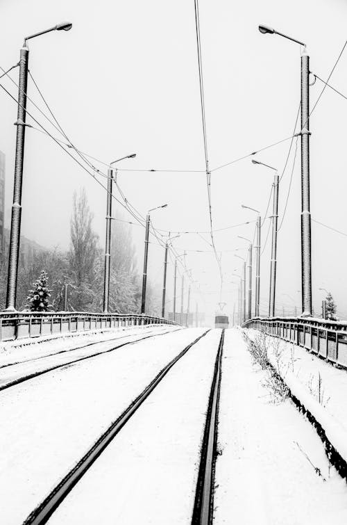 Grayscale Photo of a Train Passing a Snow Covered Train Track