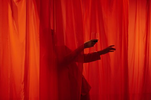 Man with Glass of Wine among Red Curtains