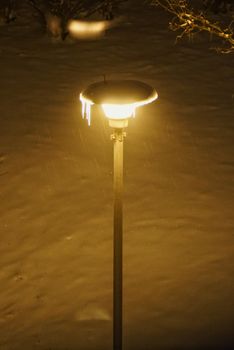 A glowing street lamp with icicles in a snowy setting, capturing winter night ambiance.