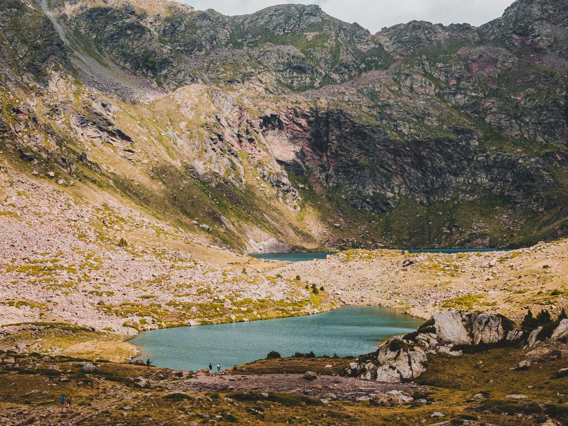 Breathtaking view of mountains encircling a tranquil turquoise lake, capturing nature's raw beauty.