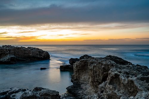 Free A breathtaking sunrise over a rocky coastline, capturing the serene beauty of the seascape. Stock Photo