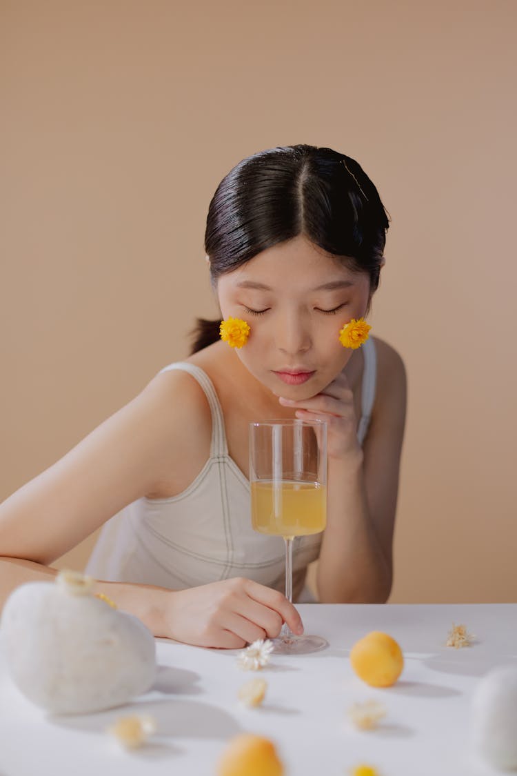 Portrait Of Black Haired Woman Holding Glass With Drink On White Table