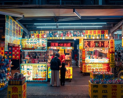 Free Colorful night market stall with neon lights and diverse street food offerings. Stock Photo