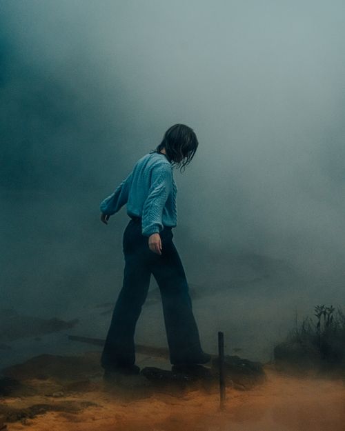 Free A woman walking through a foggy and mysterious outdoor setting, evoking a moody atmosphere. Stock Photo