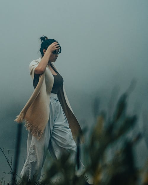 A Woman in Gray Pants Walking on the Field while Wearing a Shawl