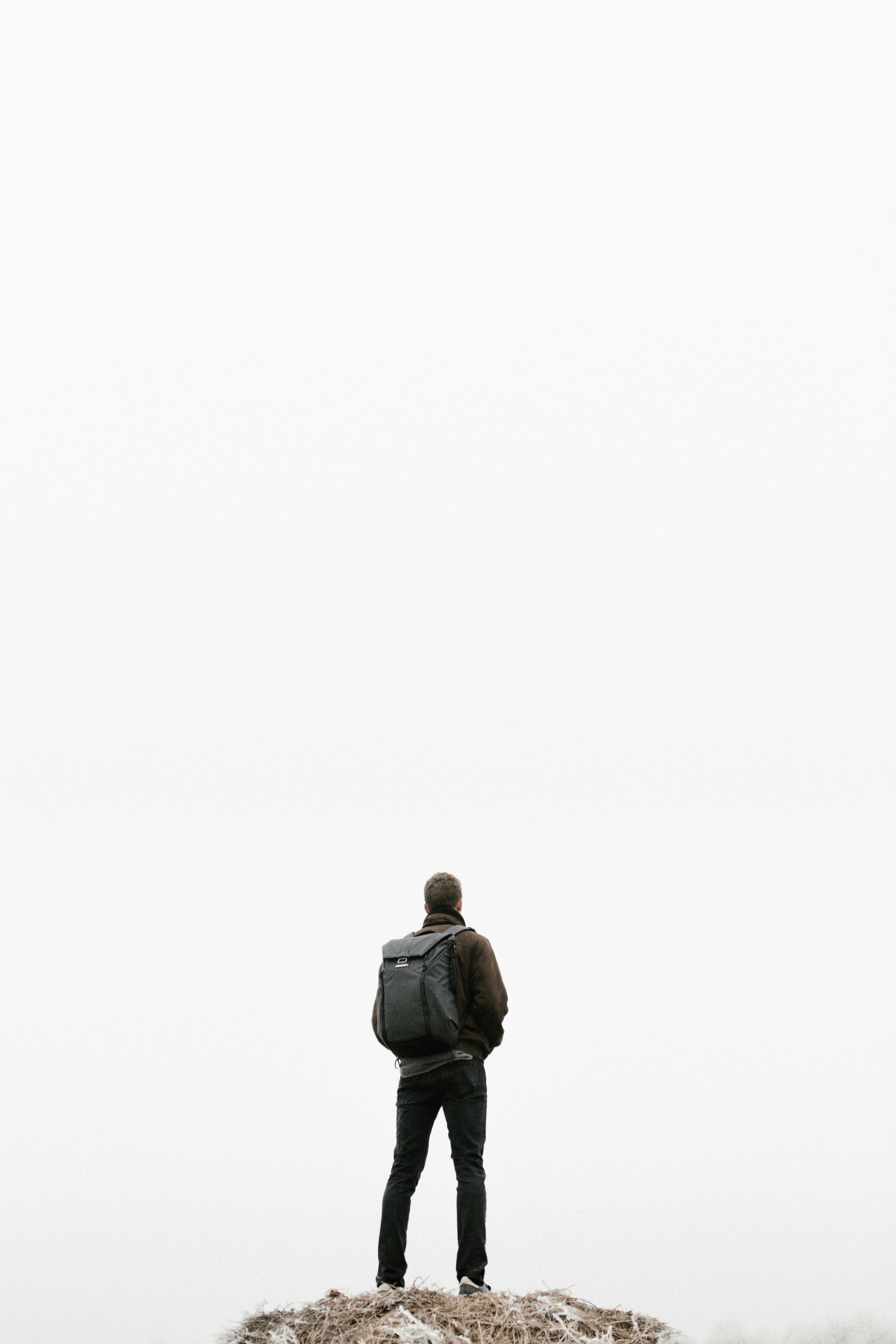 Man with backpack stands on a hill in misty Budapest, Hungary, adding to an adventurous spirit.