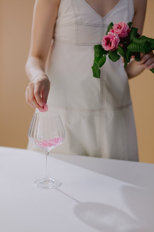 Woman in Dress Holding Rose Petal over Glass