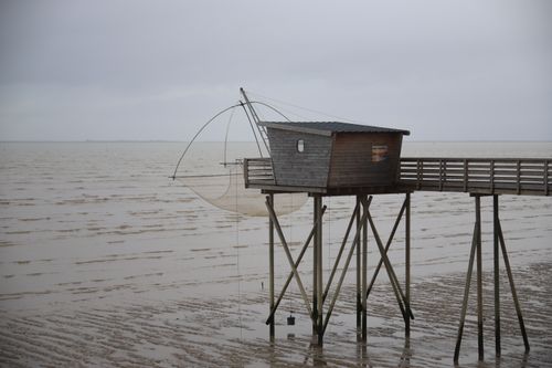 Free A wooden fishing hut on stilts over the sandy coastline of Esnandes, France, capturing coastal serenity. Stock Photo