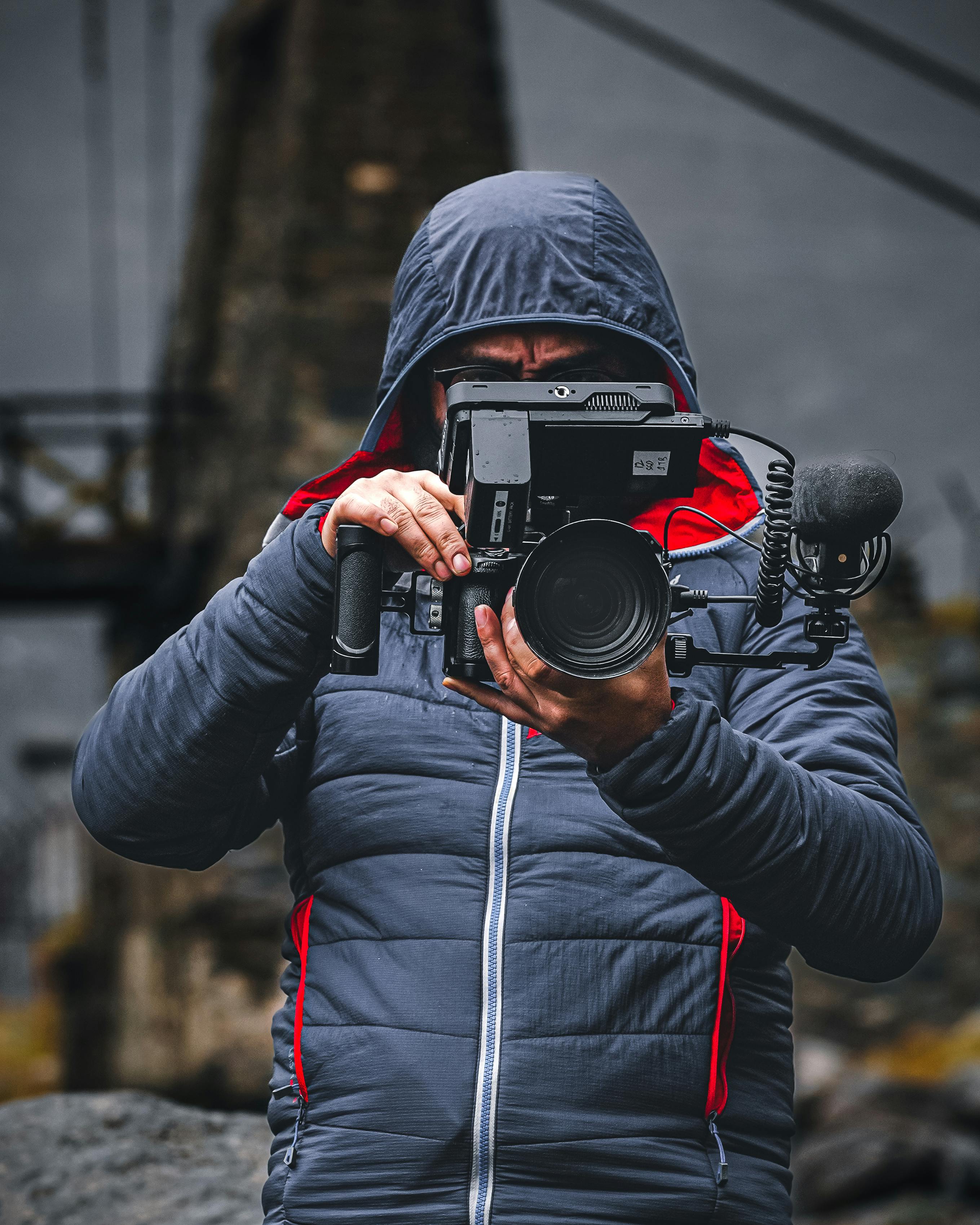 person in a blue hoodie puffer jacket holding a video camera