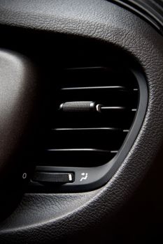 Detailed view of car interior air vent with textured plastic finish.