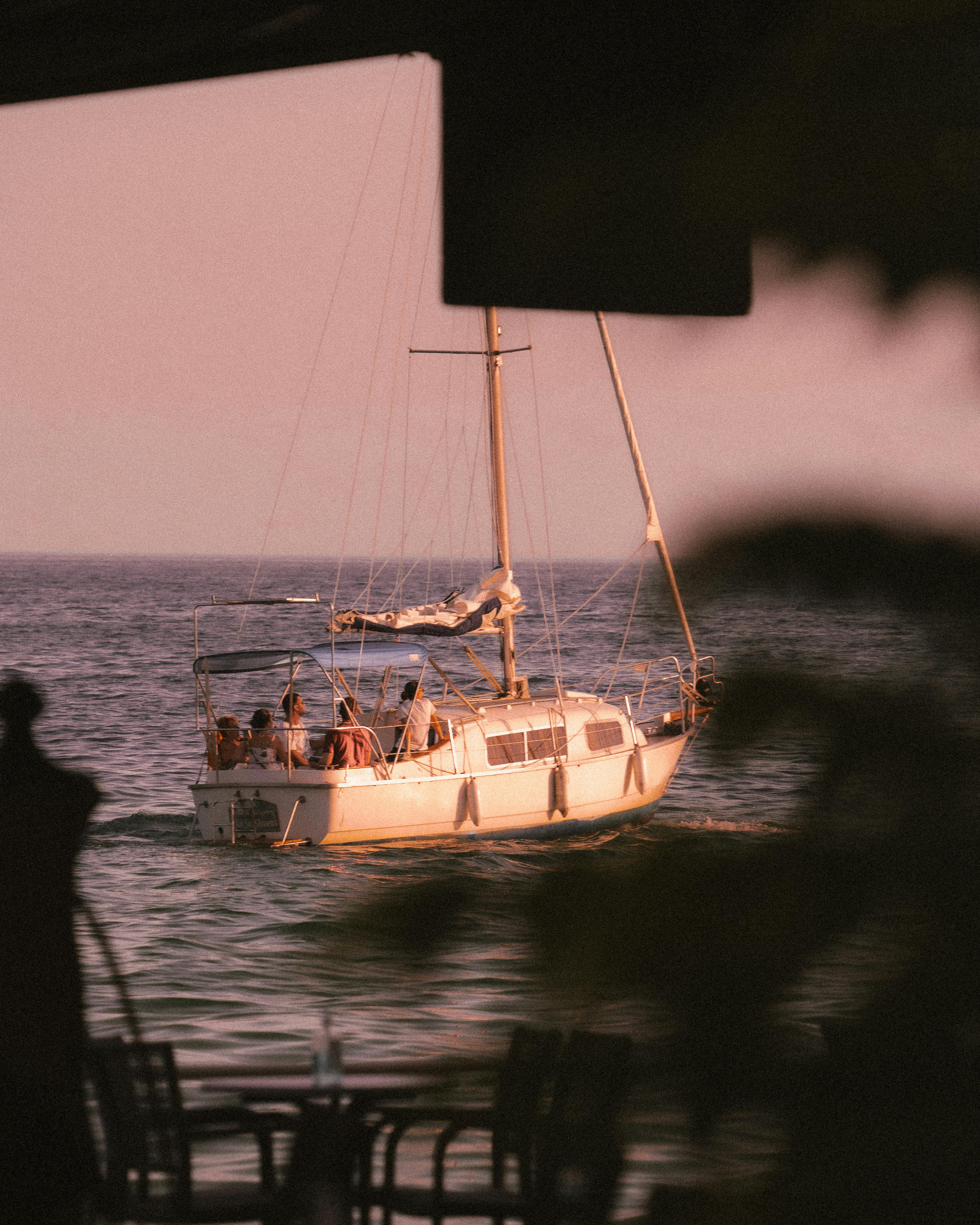 A serene scene of a sailboat cruising on the ocean during a beautiful sunset, highlighting leisure and adventure.