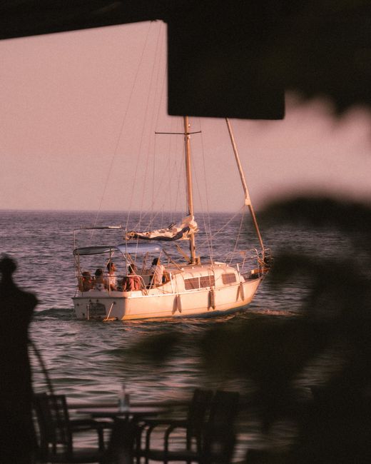 A serene scene of a sailboat cruising on the ocean during a beautiful sunset, highlighting leisure and adventure.