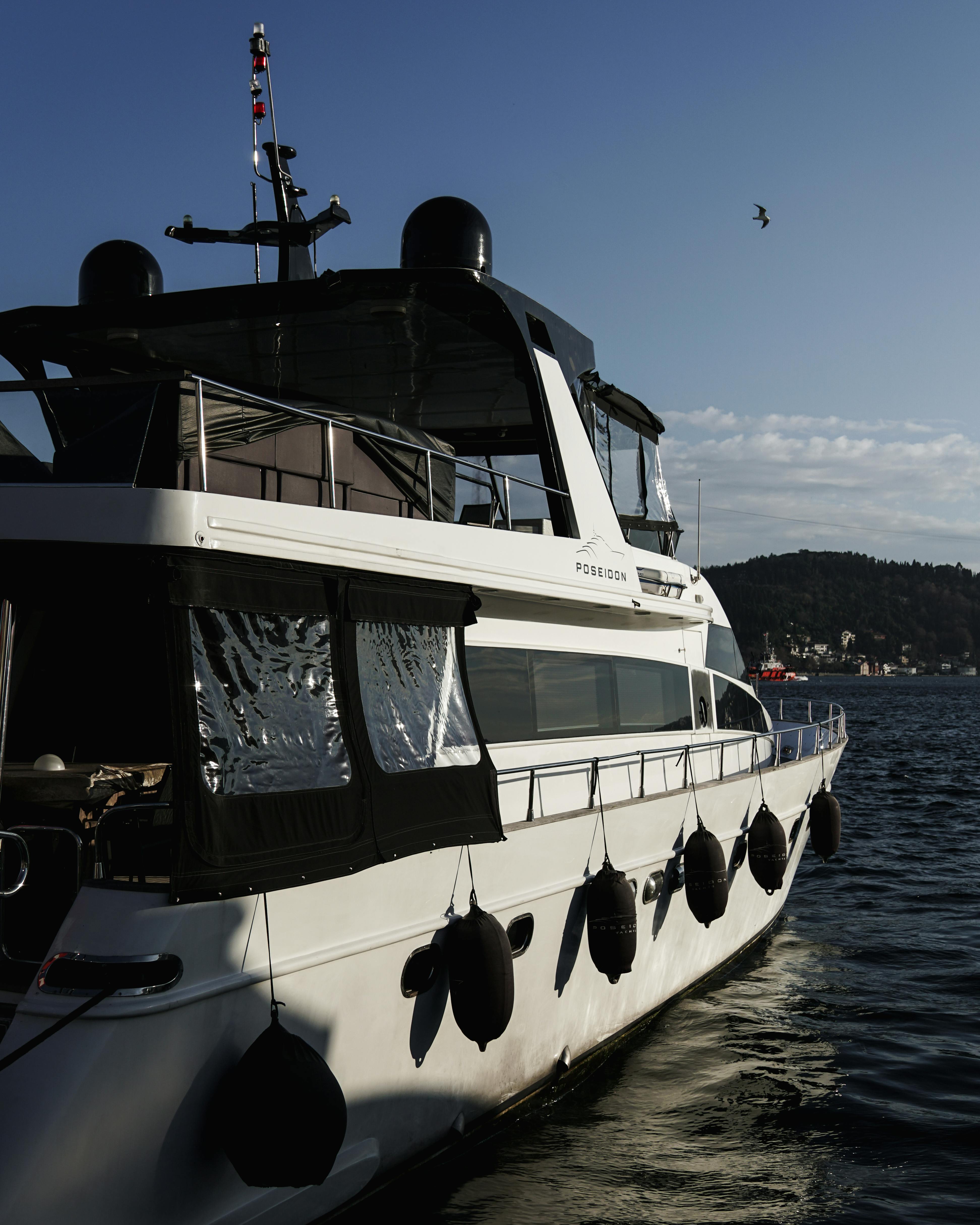 Elegant yacht docked on tranquil waters at sunset with scenic coastal backdrop.