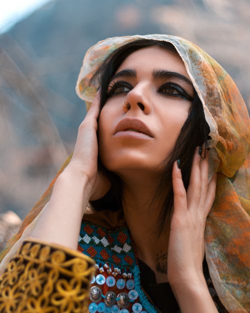 Free A striking portrait of a woman with a colorful headscarf, set against the rugged mountains of Panjshir, Afghanistan. Stock Photo