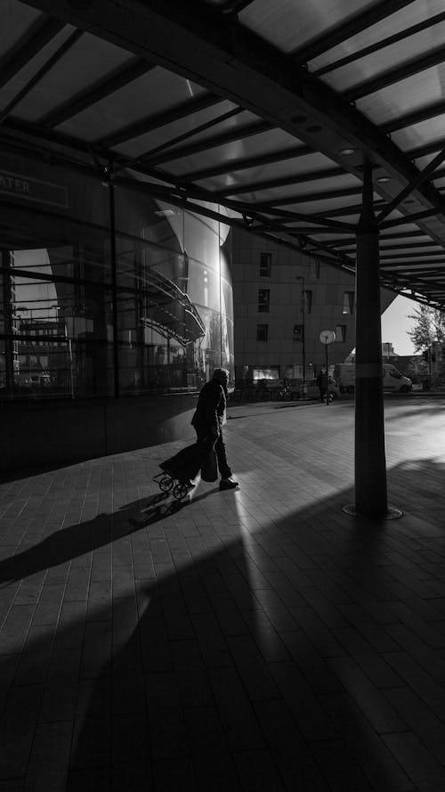 Free Man Walking on a Sidewalk Dragging a Bag on Wheels Stock Photo