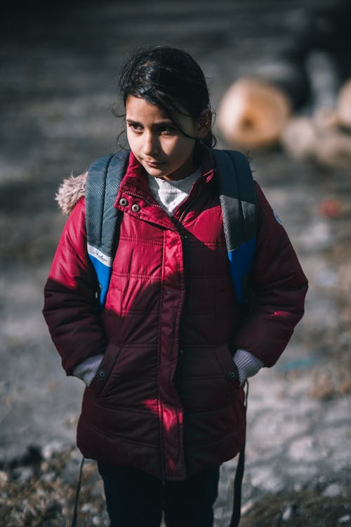 A Young Girl in Red Puffer Jacket with Her Hands in Her Pockets