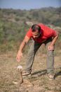 Man in Red T-shirt and Brown Pants Holding Brown Ball