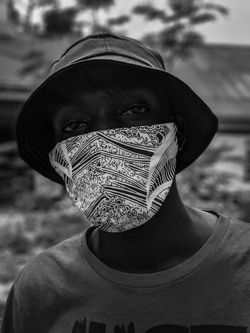 A Grayscale Photo of a Man Wearing Face Mask and Bucket Hat