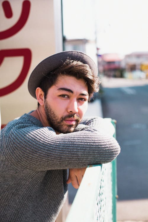 A Man in Gray Sweater Leaning on a Railing