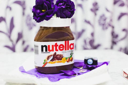 Jar of Nutella with purple flowers in a creative indoor setting.