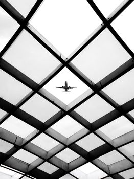 Monochrome view of a plane flying over a geometrically patterned structure in São Paulo.