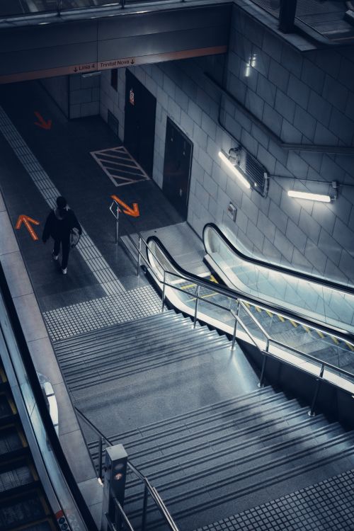 Free Dramatic high angle view of a person walking in a modern subway station with escalator and stairs. Stock Photo