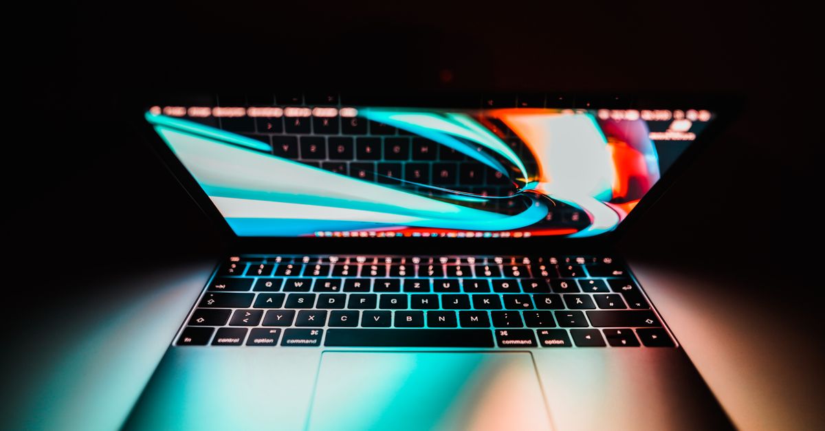 Open laptop with a colorful display reflecting on its keyboard, set against a dark background.