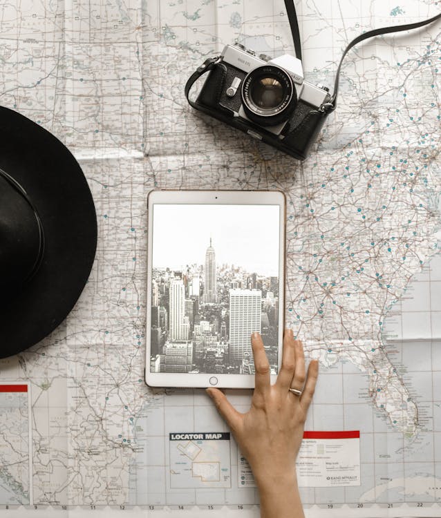 Siyah şapkanın Yanında Dünya Haritası Grafiğinde Gümüş Ipad'e Dokunan Kişinin Düz Lay Fotoğrafı