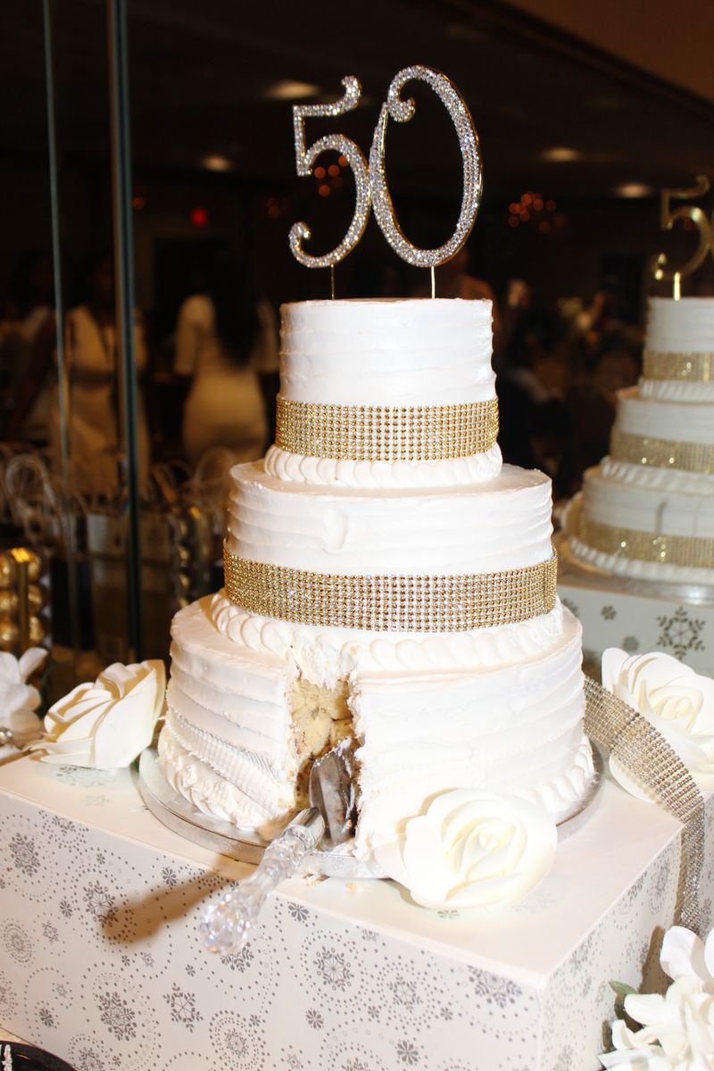 Luxurious three-tier cake with golden accents for a 50th anniversary or birthday celebration.