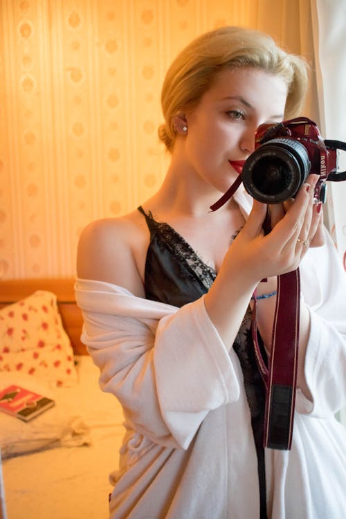 Woman Wearing Black Lace Floral Spaghetti Strap Dress Holding Black and Red Samsung Bridge Camera in Room