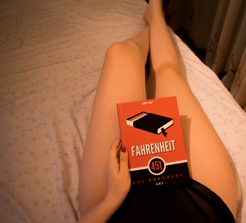 Free Person Lying on Bed Holding Fahrenheit Box Stock Photo