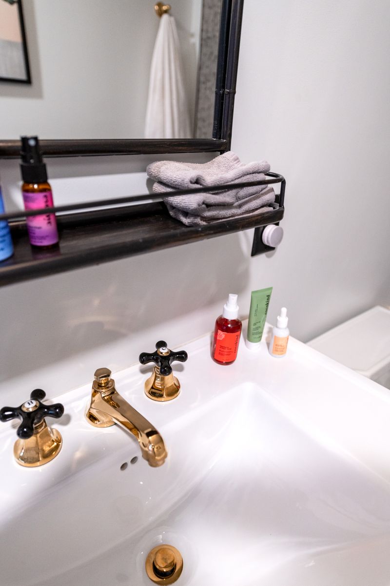 Modern bathroom sink with a gold faucet and beauty products neatly arranged on the vanity