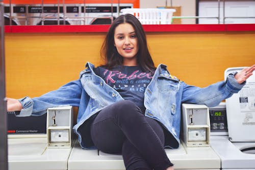 Free A Woman in Blue Denim Jacket Sitting on Top of a Washing Machine Stock Photo