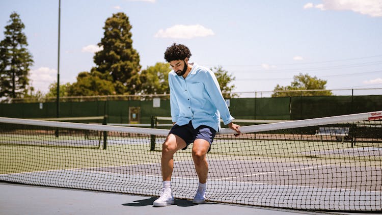 Man Sitting On Tenis Court Net