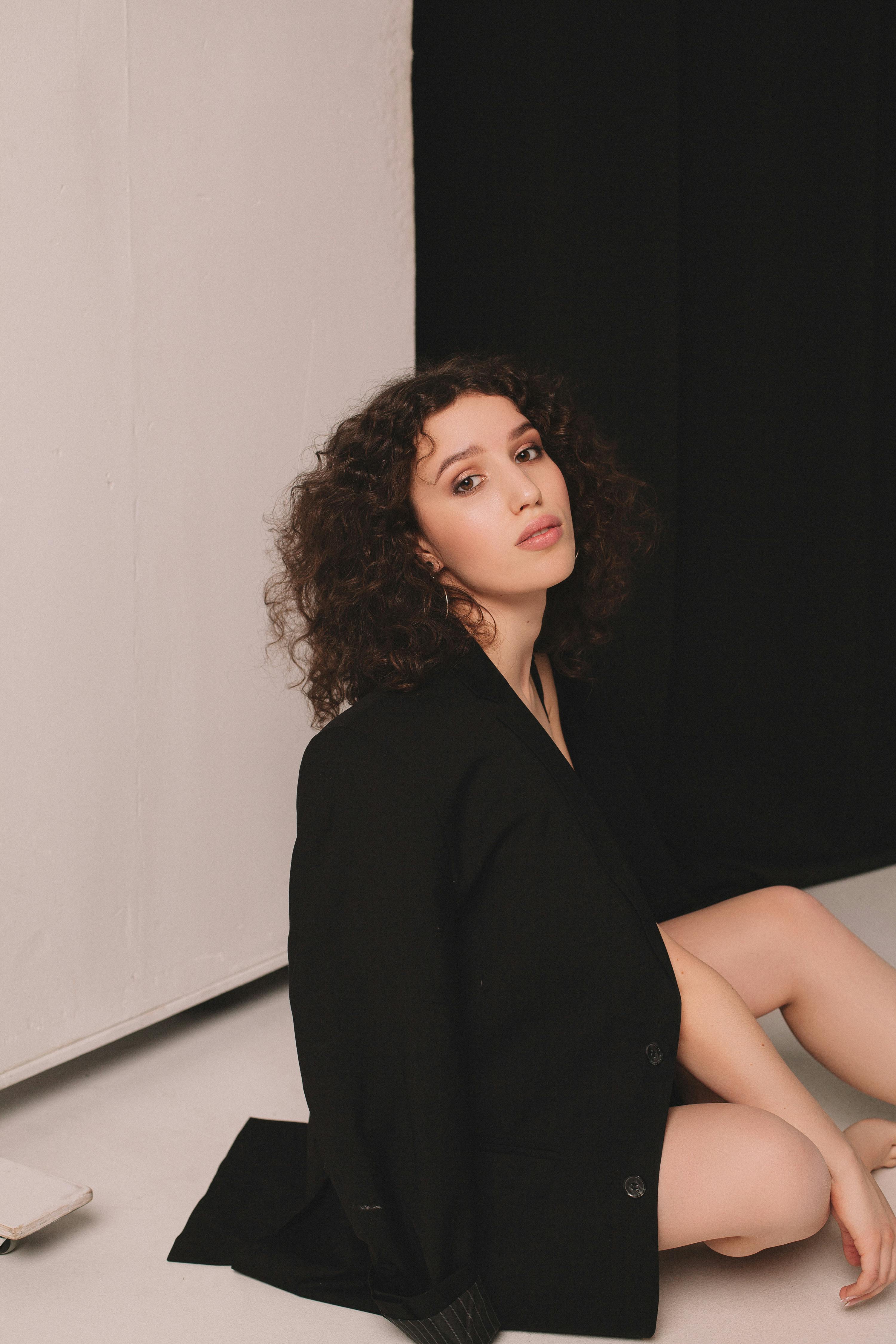 一位穿着黑色外套的卷发时尚女性坐在室内