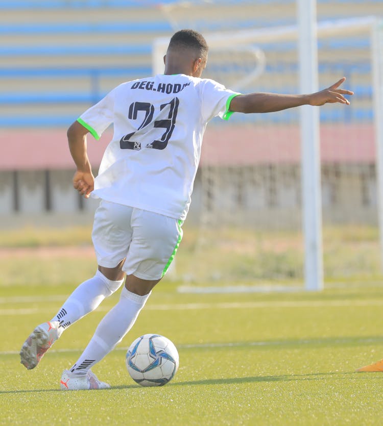 A Man In White Shirt And Shorts Playing Soccer On The Field