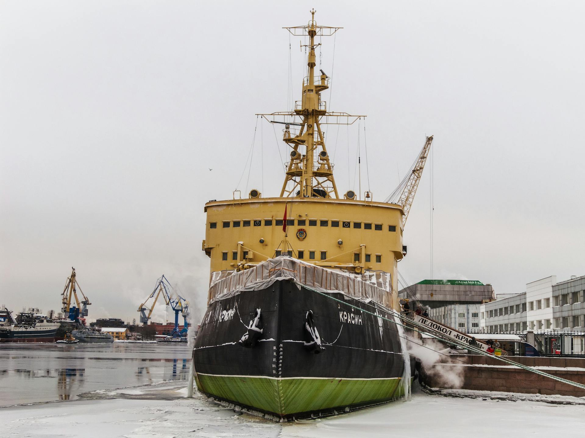 Icebreaker ship docked in a frozen harbor, highlighting cold weather and industrial elements.