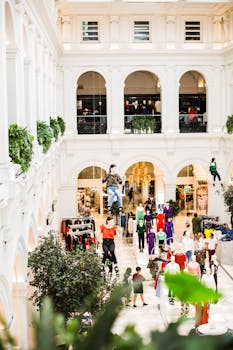 Bright view of a modern Melbourne shopping mall with decorative arches, lively crowd, and clothing displays.
