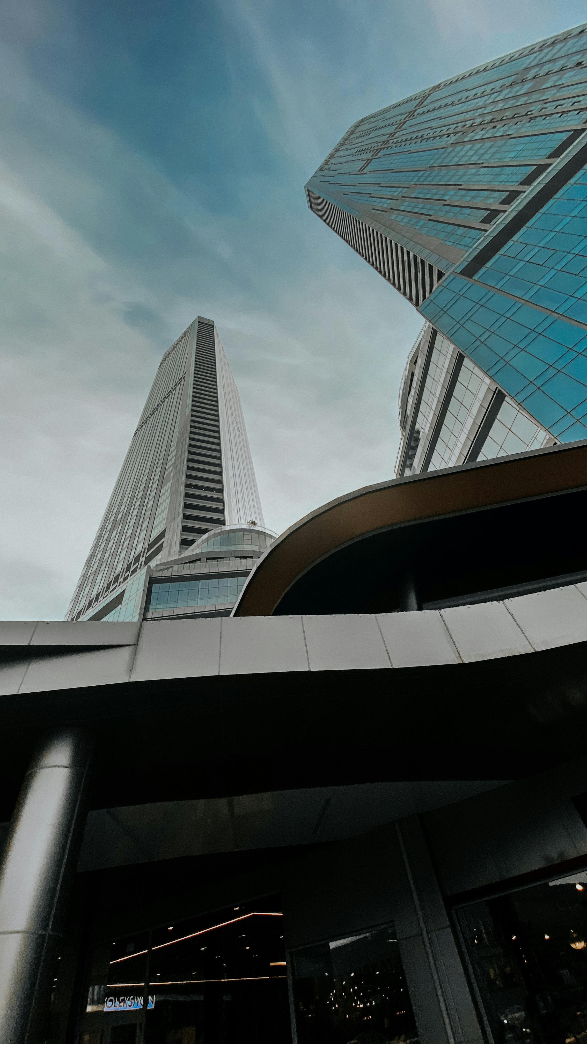 Low angle view of modern skyscrapers with glass facades against a cloudy sky.