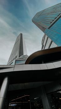 Low angle view of modern skyscrapers with glass facades against a cloudy sky.