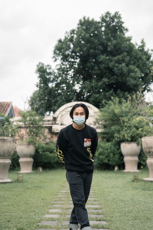 Free A man in a park in Yogyakarta wearing a face mask, represents the new normal outdoors. Stock Photo