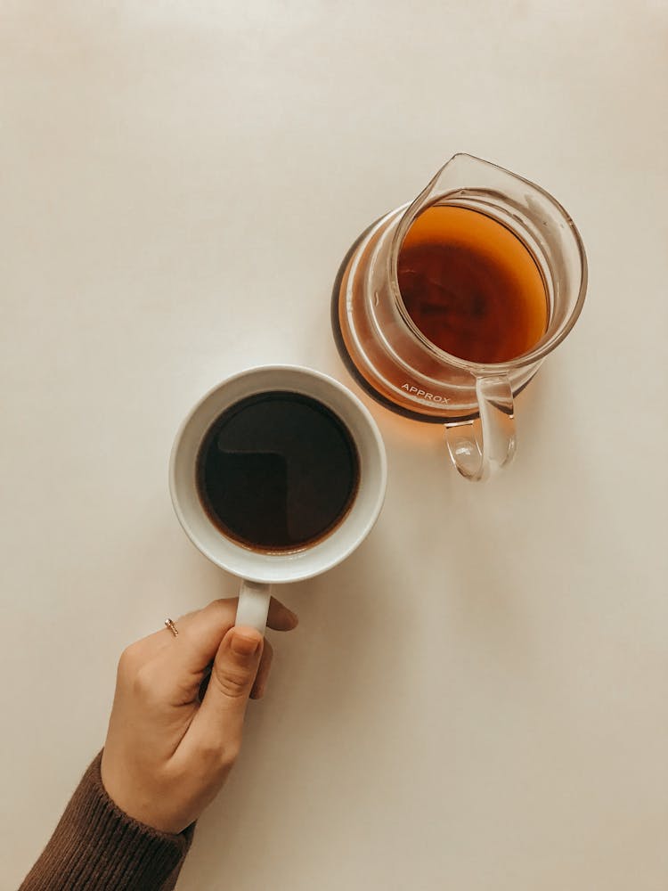 Pitcher Of Tea And A Hand Holding A Mug