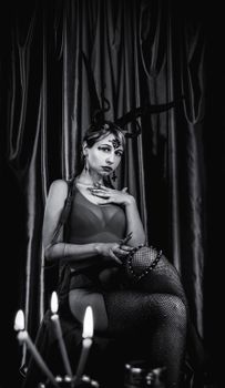 A dramatic black and white photo of a woman posing in unique costume with horns, shot in a studio setting.