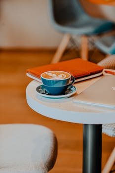 A warm cup of cappuccino on a white table in a cozy café setting, perfect for a relaxing coffee moment.
